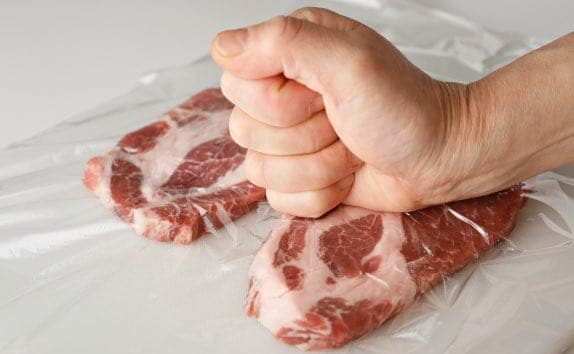 まな板に豚肉を並べて広げ、豚肉はラップをかぶせてこぶしで30回ほどたたいてのばし、6等分に切る。