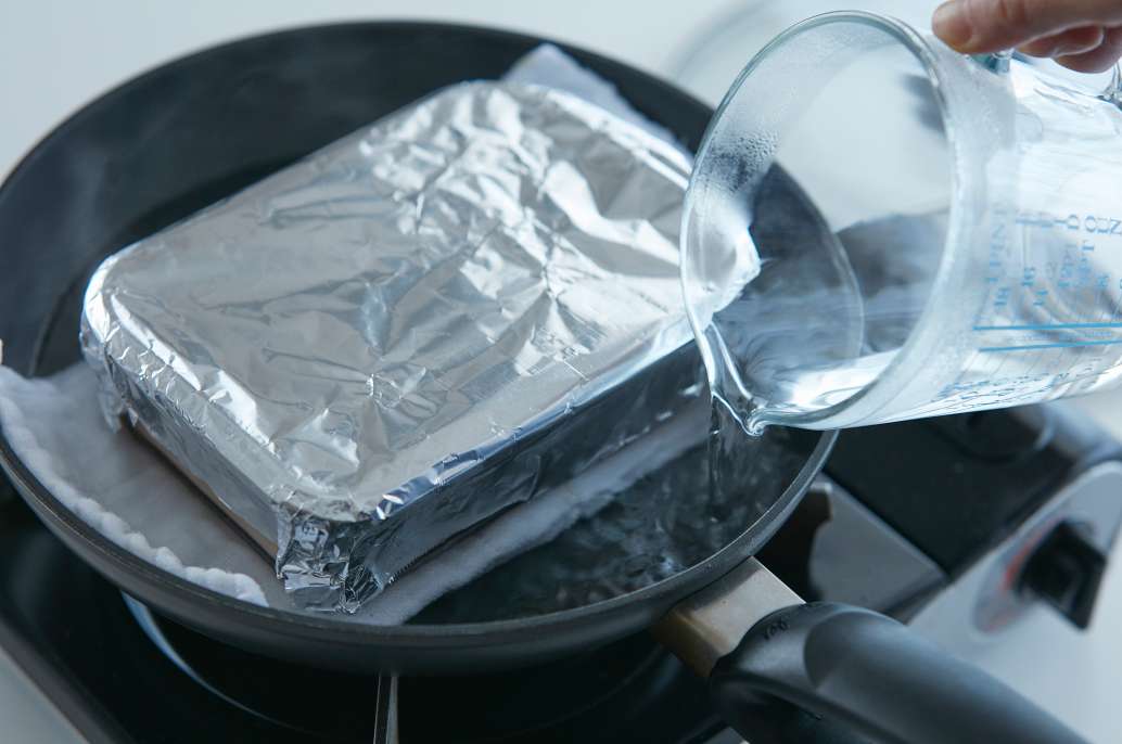 フライパンに耐熱容器をのせ、湯を注ぐ