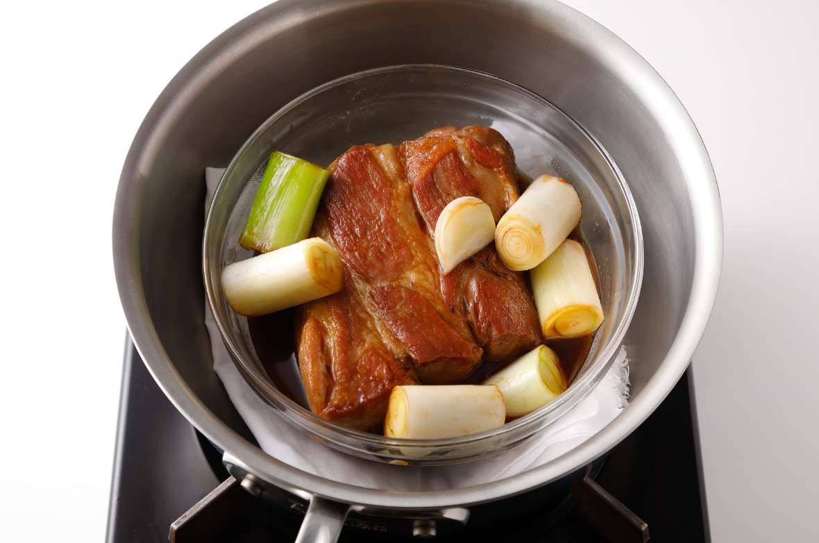 写真：鍋に豚肉のボウルを入れる