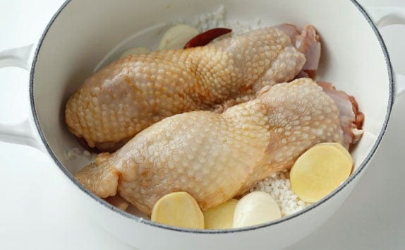 鍋に米と（A）を広げ、鶏肉をかるく丸めて入れ、水を注いで中火にかける。