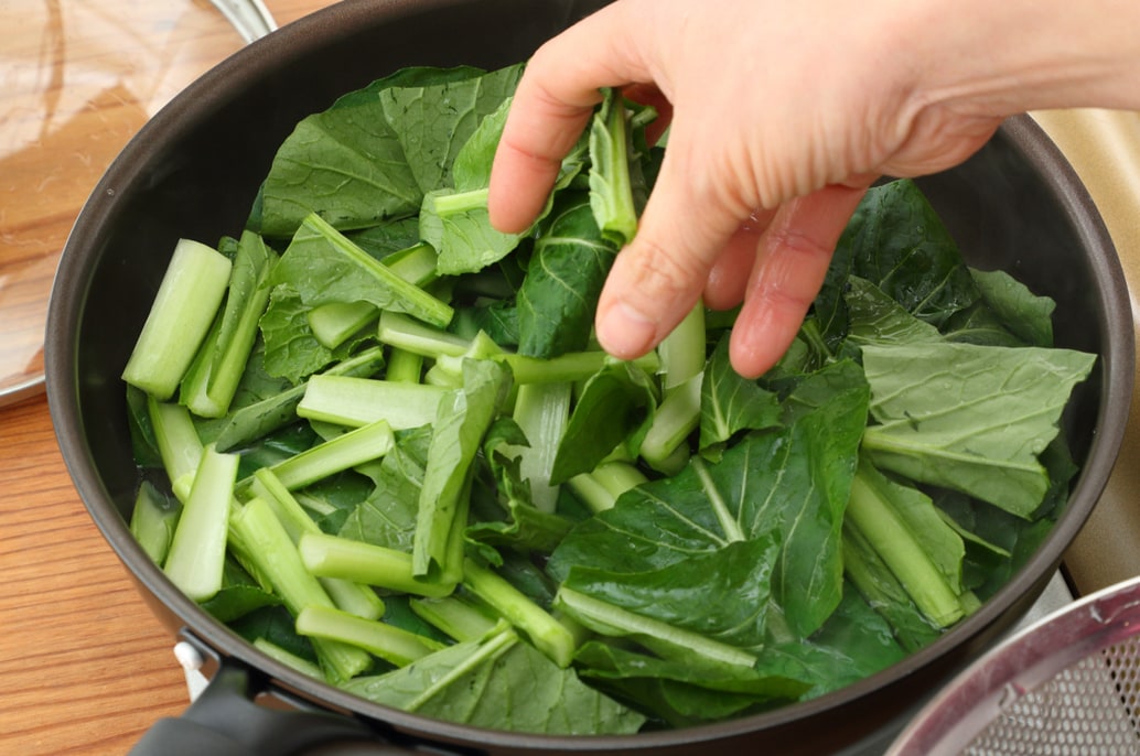 写真：フライパンに1cmほど水を入れて沸かし、切った小松菜を入れる