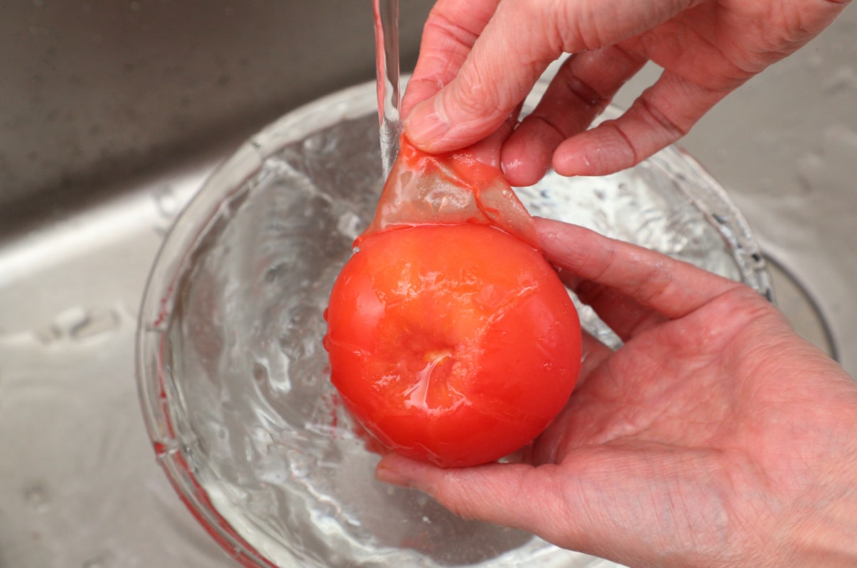 写真：冷凍されたトマトは流水で簡単に皮がむける